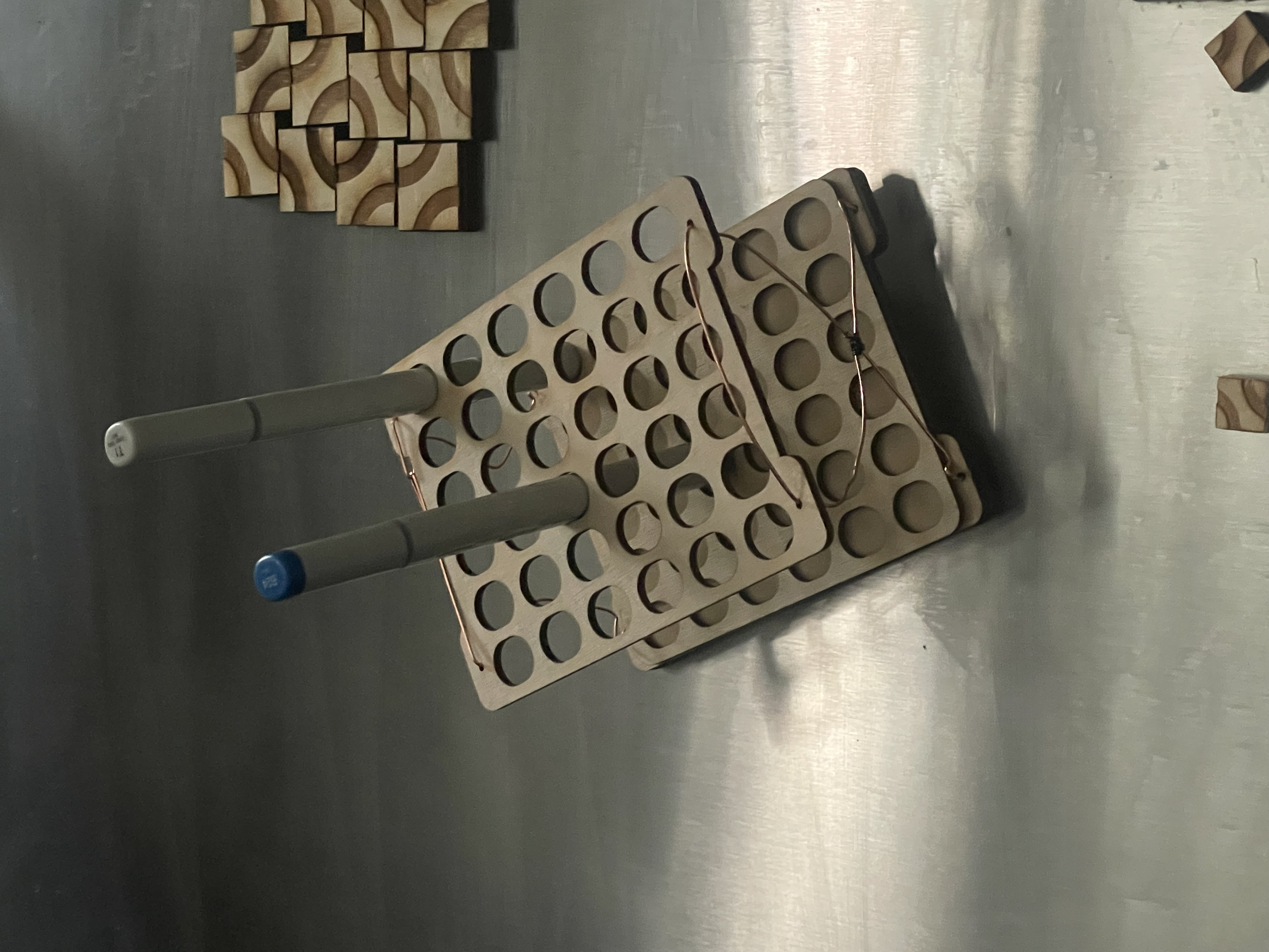 A small holder for copic markers, attached to a fridge door via hidden magnets